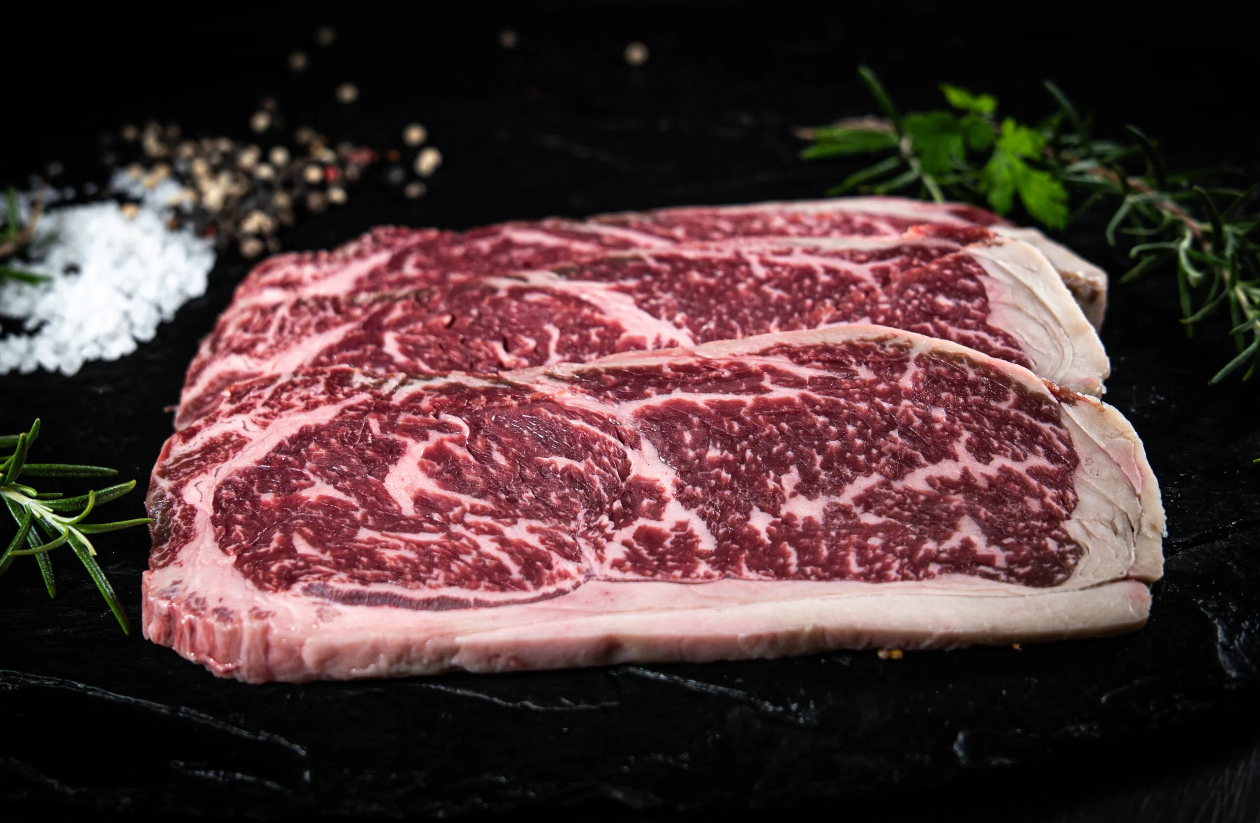 Marmorierte Striploin-Steaks auf Schiefer mit Rosmarin und grobem Salz