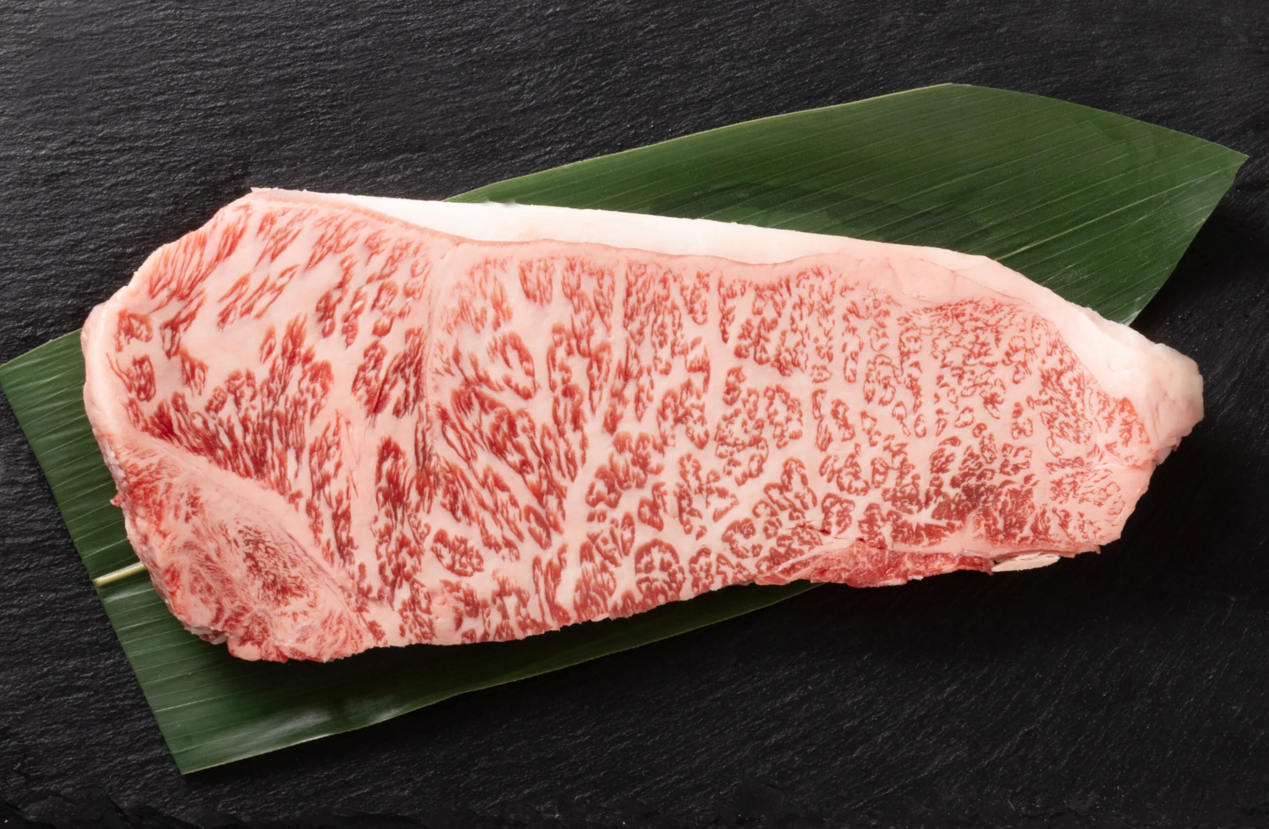 Wagyu-Striploin mit feiner Marmorierung auf einem Bambusblatt